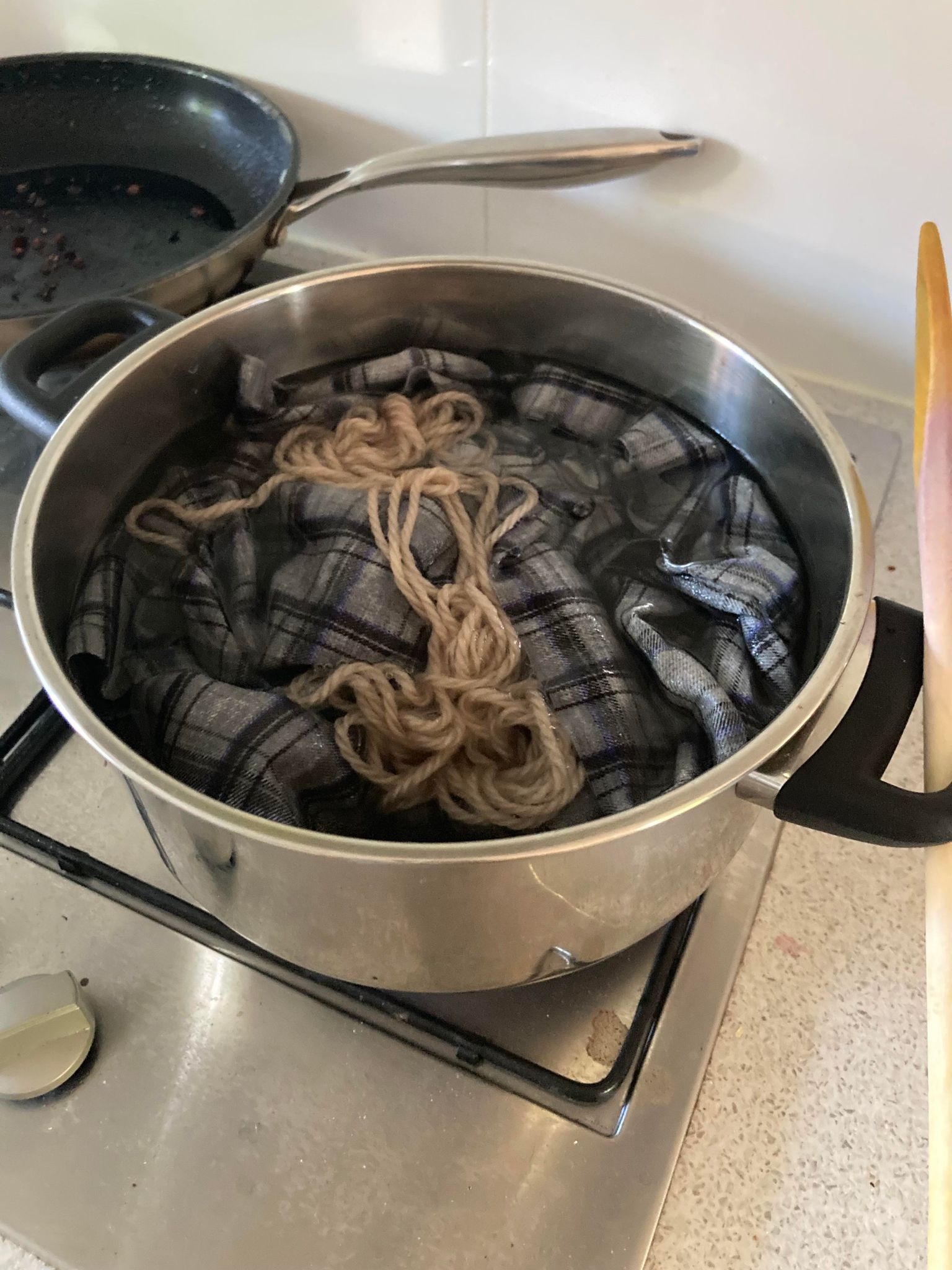 A pot of boiling plaid fabric and undyed wool yarn.